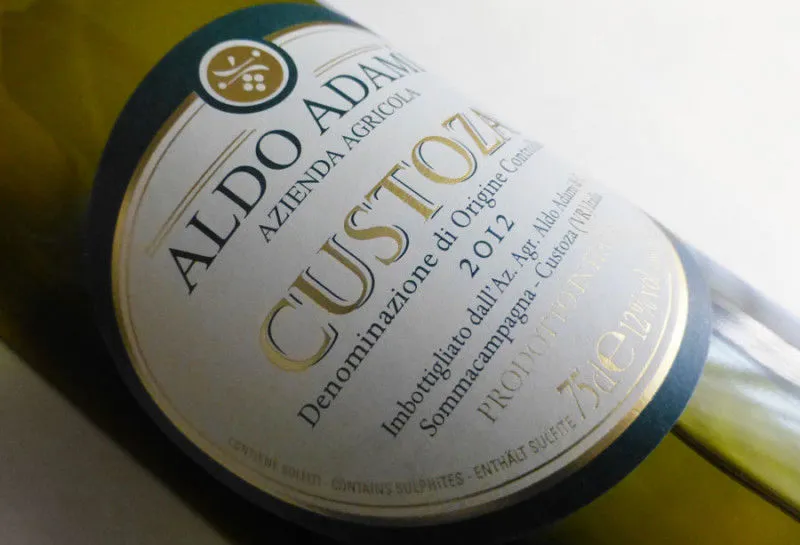 Etichetta Aldo Adami Custoza DOC con carta chiara, tipografia grigia e dettagli in oro a caldo – progetto Win&Art Verona